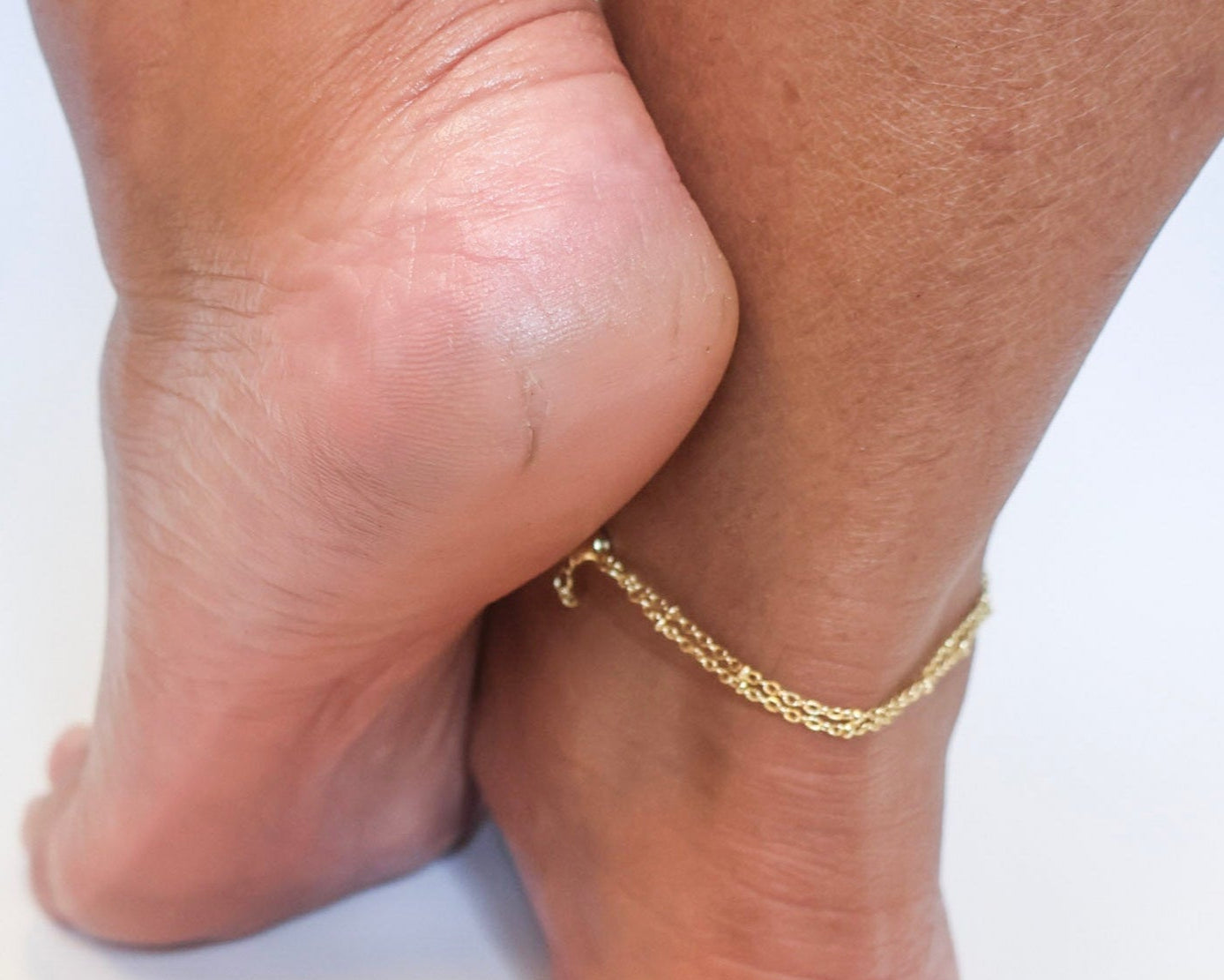 Foot with gold anklet showing smooth, crack-free heel after using dry heel repair kit. Ideal visual for cracked heel treatment results, foot care for women, and home pedicure transformation with SandBar Foot Care Kit.