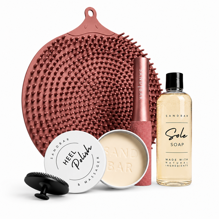 SandBar foot scrubber mat in a pink color, foot file, Sole Soap, and Heel Polish used for foot care and repair, displayed on a white background.