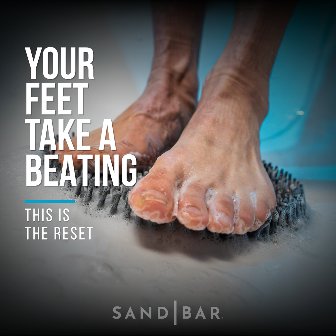 Athlete standing on foot scrubber mat in shower using SandBar foot care system