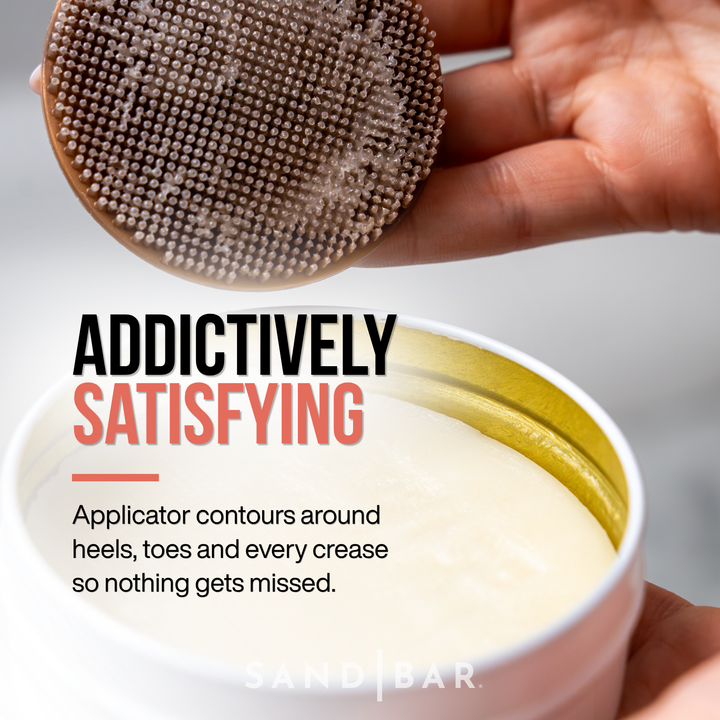 A close up of a Woman holding SandBar Heel Polish in one hand and the other hand holding the massaging applicator showing the texture loaded with Heel Polish, with bold text reading “For Heels You Can’t Stop Touching"