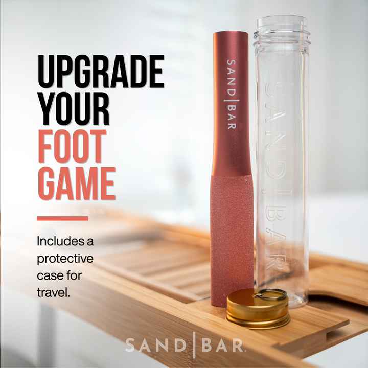 Copper pink SandBar foot file with clear acrylic protective case with the sandbar logo and gold lid on a wooden surface, showing the included case