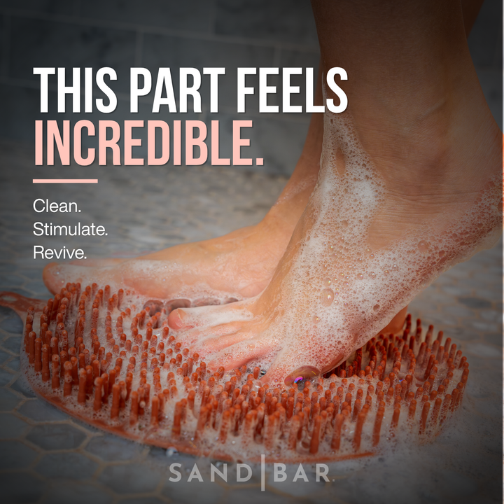 Feet using SandBar silicone foot scrubber mat with rich lather to clean stimulate and revive tired dry feet.