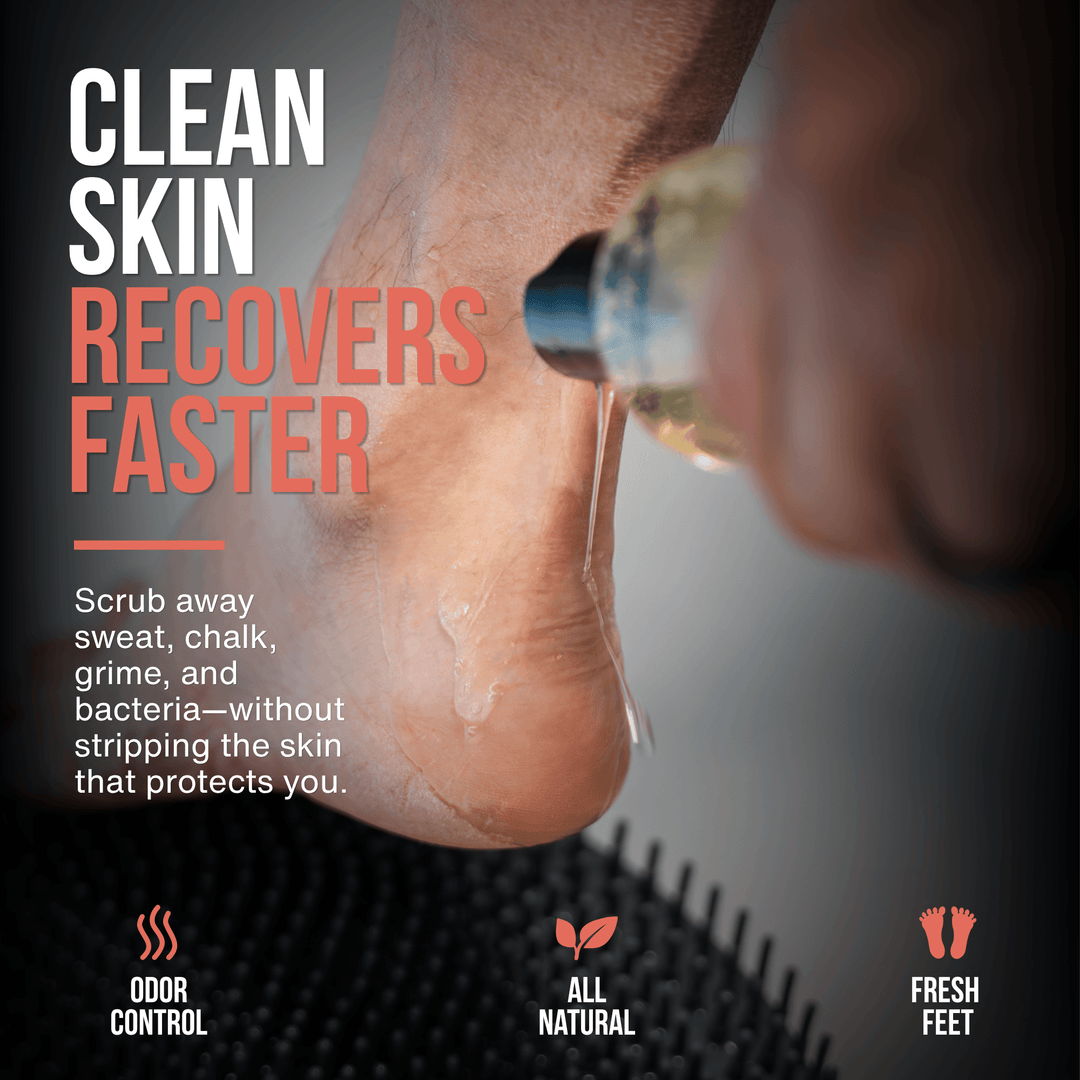 Close-up of Sole Soap being applied to a heel above the SandBar shower foot scrubber mat to wash away sweat, grime and buildup. Text reads “Clean Skin Recovers Faster.”