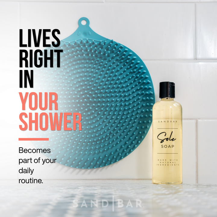 Teal Foot scrubber mat and bottle of Sole soap hanging on a tiled shower wall for smoother softer feet at home.